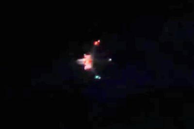 blurry and dark photo of the bottom of an airplane that is speculated to be a drone, red lights underneath.