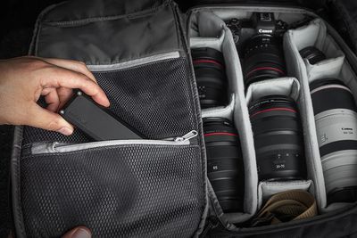 A person puts the Elevation Lab TimeCapsule in a pocket inside a camera bag.